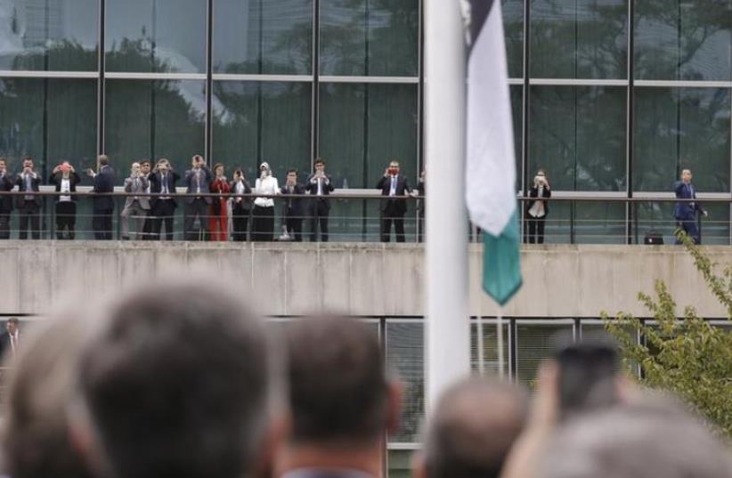 Onlookers take photographs as the Palestinian flag is being raised by Palestinian President Mahmoud Abbas (not pictured) in a ceremony outside the United Nations during the 70th session of the U. N. General Assembly in New York, September 30, 2015. Even though Palestine is not a member of the United (photo credit: REUTERS)