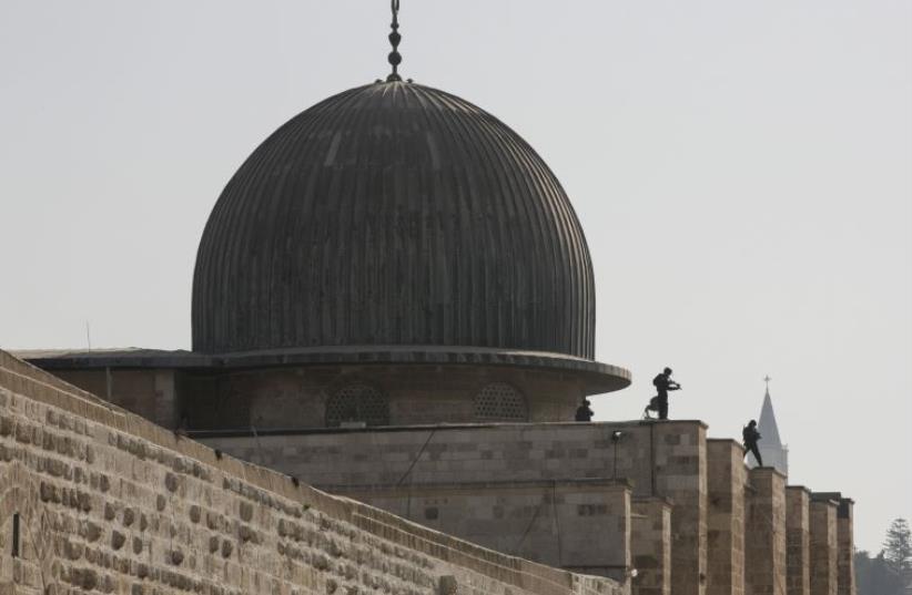 Israeli police officers take positions on the roof of the al-Aksa mosque during clashes with Palestinians in Jerusalem's Old City (photo credit: REUTERS)