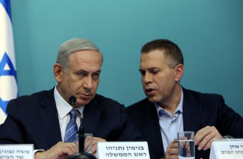 Prime Minister Benjamin Netanyahu listens to Public Security Minister Gilad Erdan (R) during a press conference in Jerusalem (photo credit: AFP PHOTO)