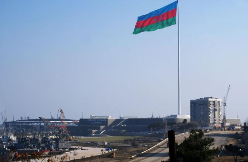An enormous Azerbaijani flag flies above the construction site of a landmark concert hall on the Caspian Sea shoreline in Baku (photo credit: SAMIR ALIYEV/AFP)