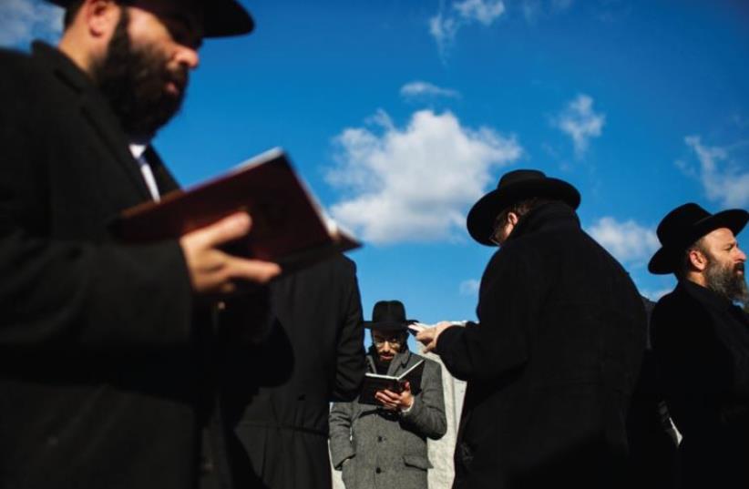 MEN PRAY at the gravesite of the Lubavitcher Rebbe, Rabbi Menachem M. Schneerson, in the Queens borough of New York Last November. (photo credit: REUTERS)