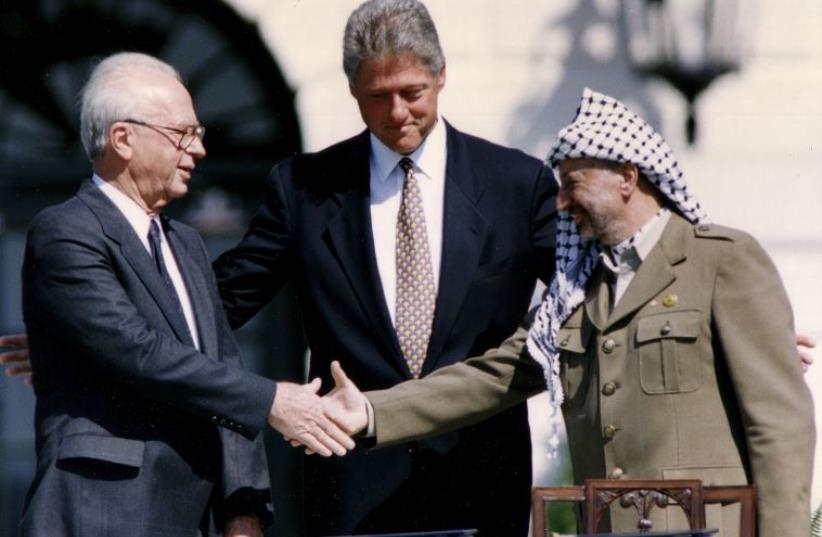 Then-PLO Chairman Yasser Arafat (R) shakes hands with then-prime minister Yitzhak Rabin (L), as U.S. President Bill Clinton stands between them (photo credit: REUTERS)