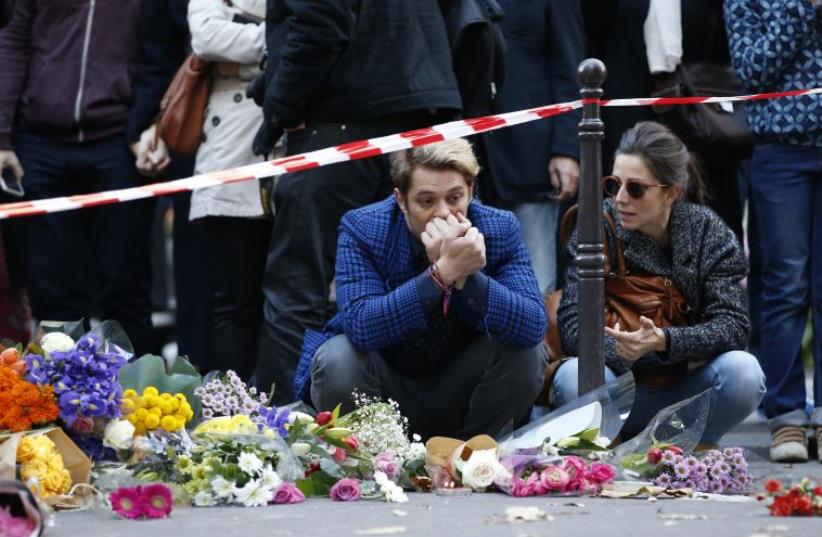 Mourners gather at memorial sites outside of the Casa Nostra restaurant and the cafe "Bonne biere" in Paris, on November 15, 2015, following a series of coordinated attacks in and around Paris on November 13 (photo credit: PATRICK KOVARIK / AFP)