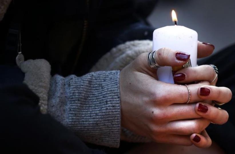 A woman holds a candle as she pays her respect at one of the attack sites in Paris, November 15, 2015.  (photo credit: REUTERS)