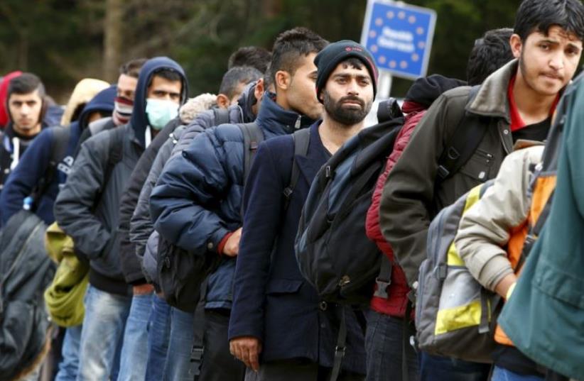 Migrants stay in a queue before passing the Austrian-German border (photo credit: REUTERS)