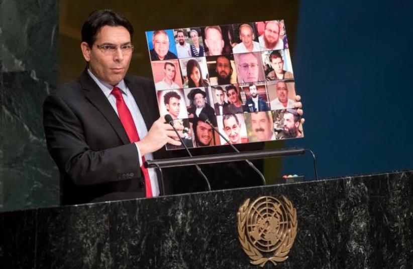 Israel's ambassador to the UN, Danny Danon, holds up a collage of Israeli victims of Palestinian terrorism (photo credit: UN)