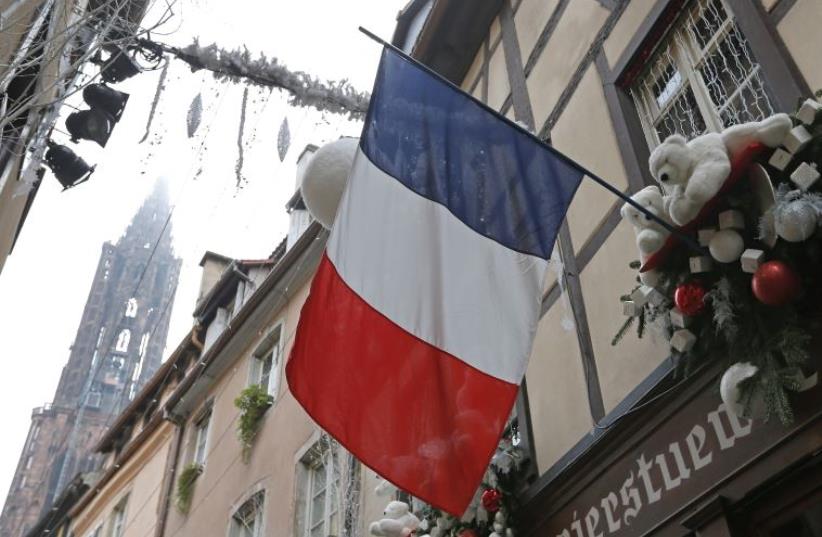 A French flag hangs from a window of a restaurant decorated for Christmas holiday season in Strasbourg, France (photo credit: REUTERS)