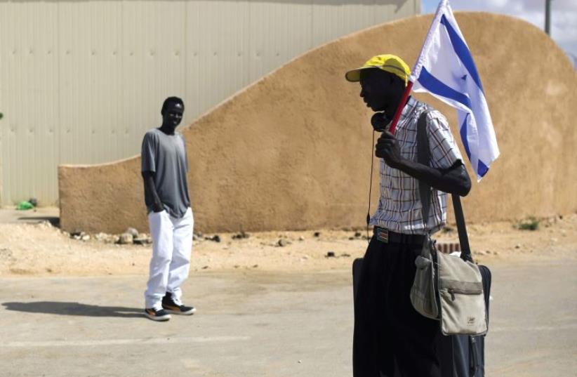 An African migrant holds an Israeli flag after being released from the Holot detention center in the Negev (photo credit: REUTERS)