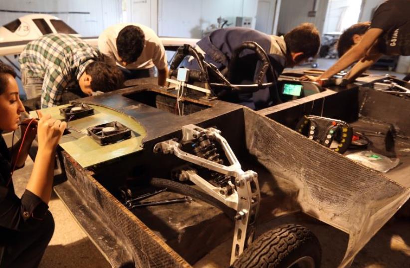 Students at Qazvin Azad Islamic University, west of Tehran, assemble a solar-powered Havin-2 vehicle for a test drive (photo credit: ATTA KENARE / AFP)