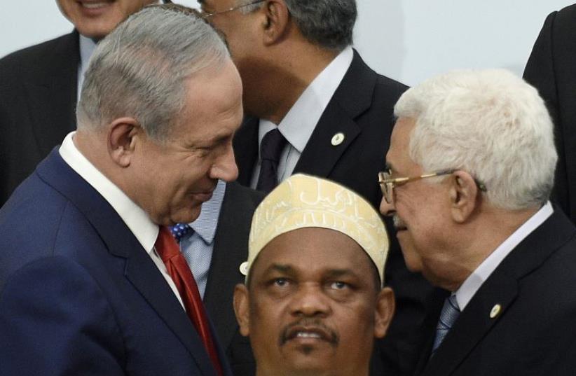 PM Netanyahu talks with President Abbas during a family photo for the opening day of the World Climate Change Conference 2015  (photo credit: REUTERS)