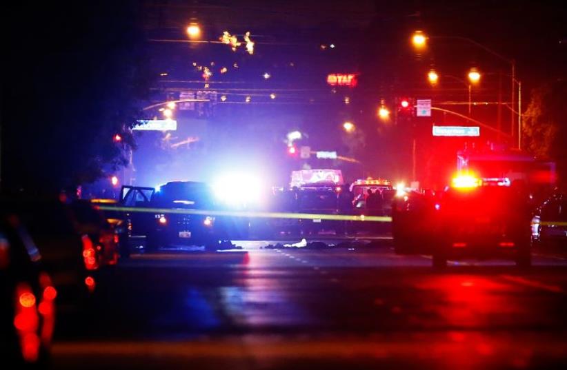 Police vehicles line the street around a vehicle in which two suspects were shot following a mass shooting in San Bernardino, California (photo credit: REUTERS)