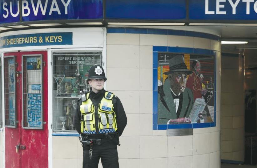 A police officer patrols outside Leytonstone Underground station in east London (photo credit: REUTERS)