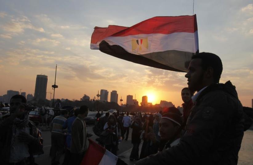 People stand on a bridge overlooking the river Nile as many Egyptians walk on the streets with Egyptian flags in Cairo (photo credit: REUTERS)