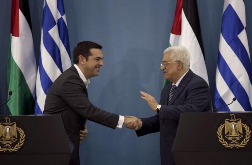 Greek Prime Minister Alexis Tsipras (L) shakes hands with Palestinian Authority President Mahmoud Abbas during a news conference in the West Bank city of Ramallah (photo credit: REUTERS)