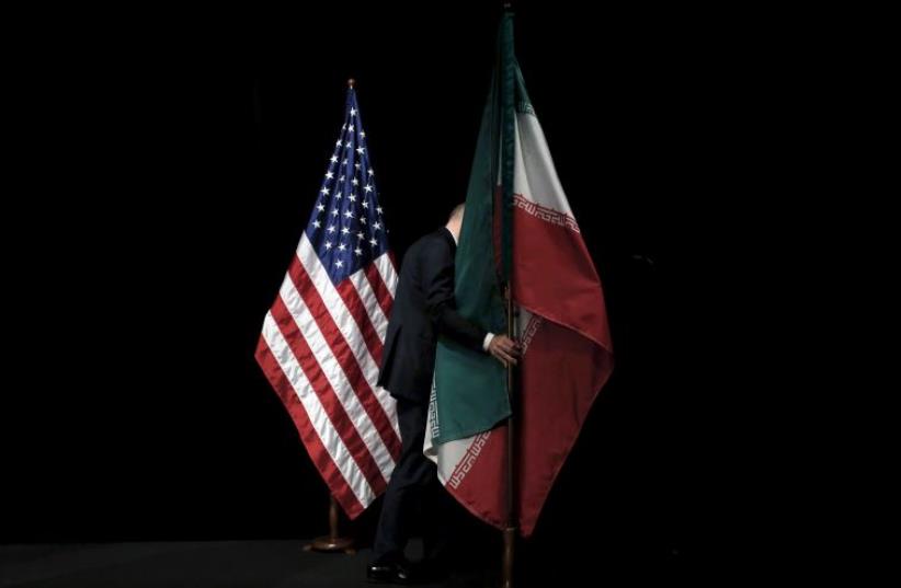 A staff member removes the Iranian flag from the stage during the Iran nuclear talks in Vienna, Austria July 14, 2015 (photo credit: REUTERS)