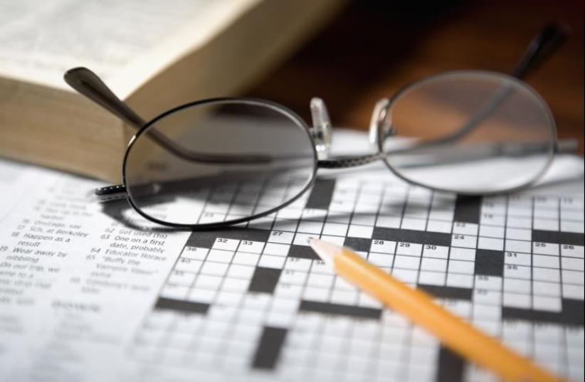 Close-up of a pencil and a pair of eyeglasses on a crossword puzzle (photo credit: INGIMAGE)