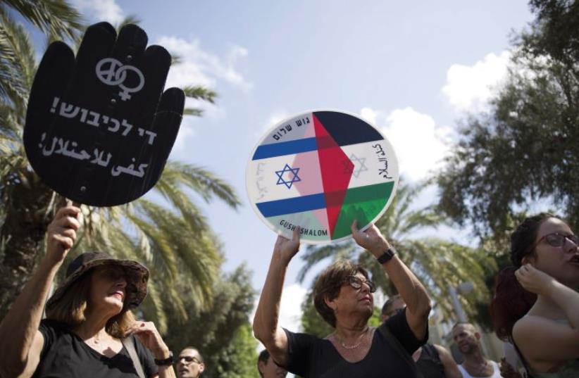 Left - wing protesters hold placards during a demonstration in Tel Aviv (photo credit: REUTERS)