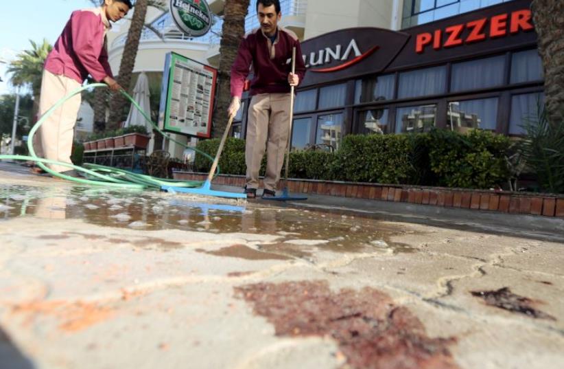 Cleaners try to clean blood stains near the entrance to Bella Vista Hotel in the Red Sea resort of Hurghada, Egypt, January 9, 2016. (photo credit: REUTERS)