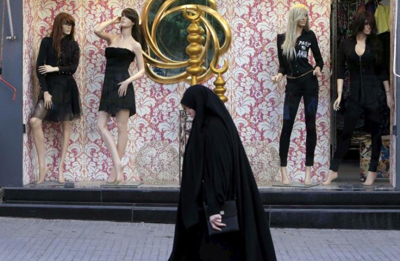Woman wearing an abaya walks past a fashion clothing store in Lebanon (photo credit: REUTERS)