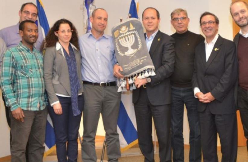 JERUSALEM MAYOR Nir Barkat holds a Torah that was donated in honor of Shira in a ceremony at the capital’s City Hall yesterday. (photo credit: JEKI LEVI)