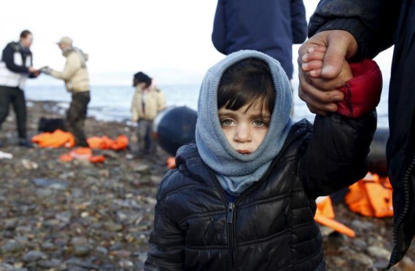 A Syrian refugee child looks on, moments after arriving on a raft with other Syrian refugees on a beach on the Greek island of Lesbos (photo credit: REUTERS)