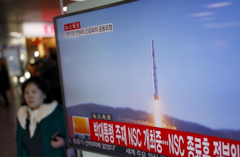 A passenger walks past a TV screen broadcasting a news report on North Korea's long range rocket launch (photo credit: REUTERS/KIM HONG-JI)