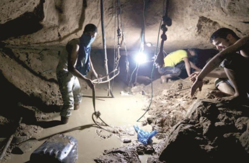Gazans repair a smuggling tunnel, flooded by the Egyptians, beneath the border between Egypt and Gaza, November 26. (photo credit: REUTERS)