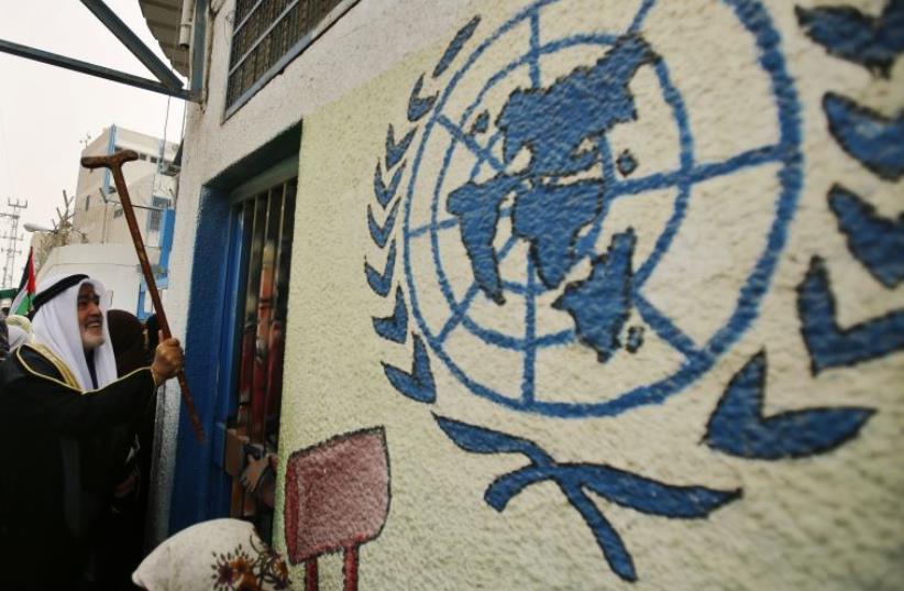 A Palestinian refugee knocks on the closed gate of the United Nations Relief and Works Agency (UNRWA) headquarters with his walking stick (photo credit: REUTERS)