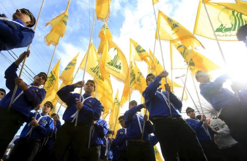 Lebanon's Hezbollah scouts carry their parties flag while marching at the funeral of three Hezbollah fighters who were killed in Syria (photo credit: REUTERS)