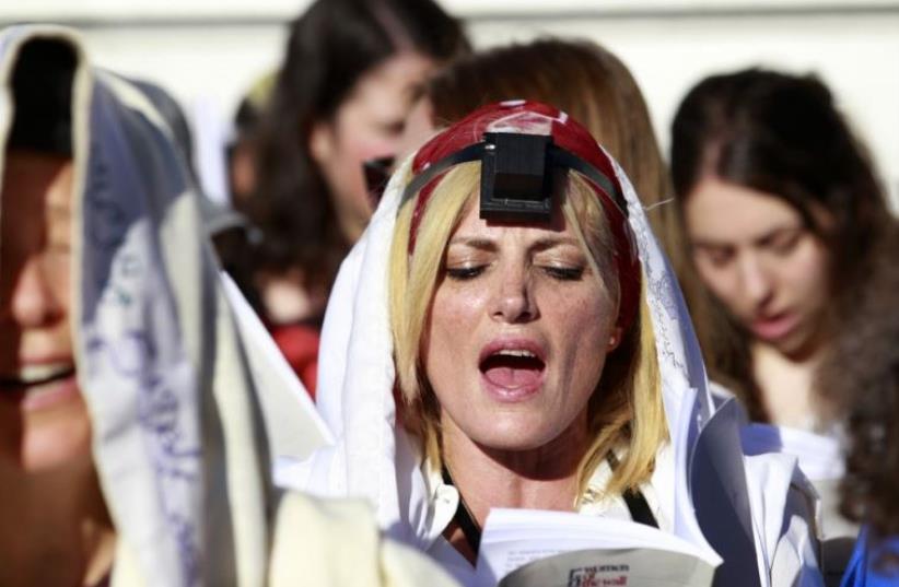 A Jewish female activist (C) from the Women of the Wall prayer rights group wears a prayer shawl and tefillin during a monthly prayer session near the Western Wall plaza in Jerusalem (photo credit: REUTERS)