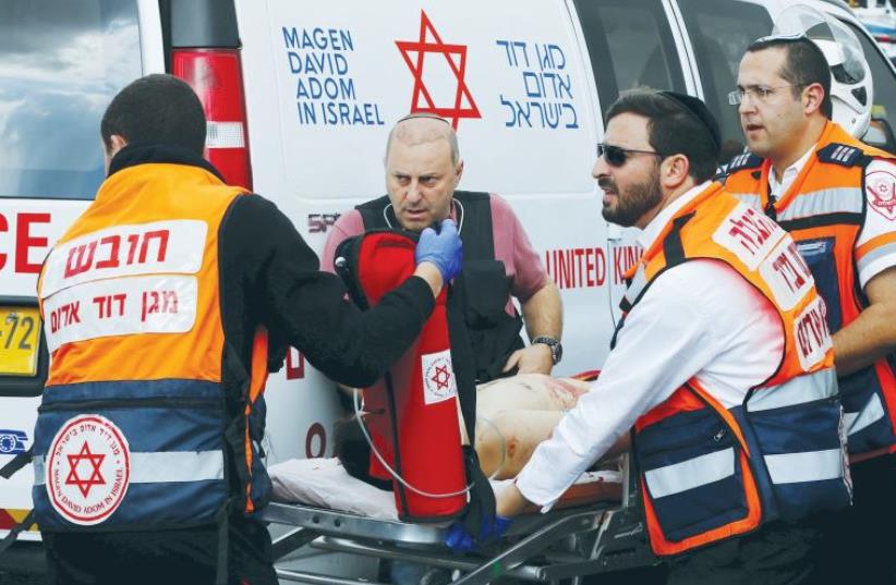 MDA MEDICS evacuate a Palestinian attacker in Jerusalem after a stabbing in October (photo credit: REUTERS)