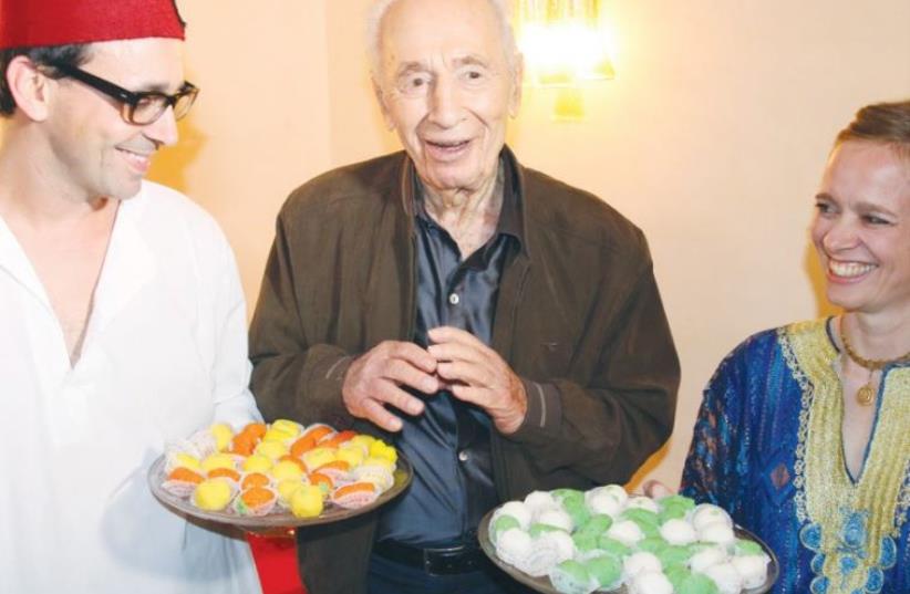 FORMER PRESIDENT Shimon Peres enjoys a post-Passover sweet at a Mimouna celebration in Tel Aviv yesterday. (photo credit: ELAD MALKA)