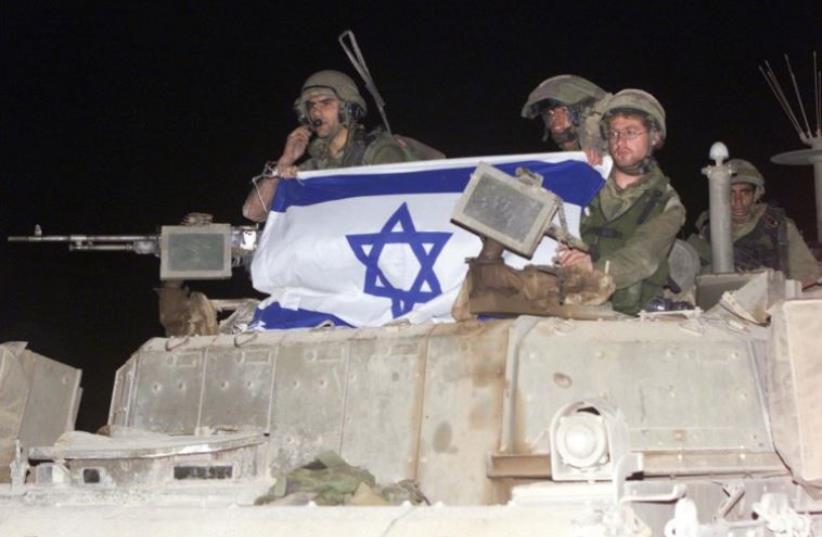 Israeli soldiers crossing the border with Lebanon into Israel on an armoured personal carrier on May 24, 2000 (photo credit: AFP PHOTO)