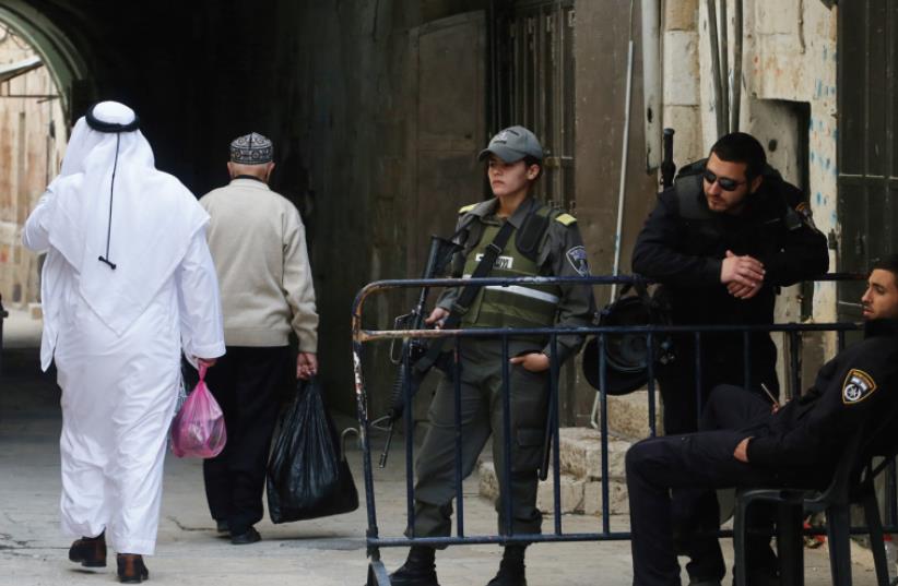 A SPLIT CITY: Two Arab men walk past police officers in the Old City of Jerusalem (photo credit: MARC ISRAEL SELLEM)