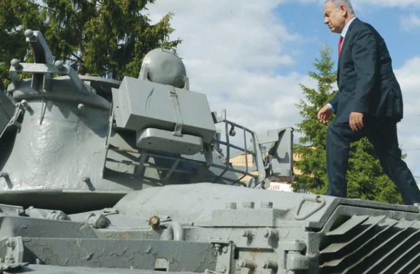 PRIME MINISTER Benjamin Netanyahu walks atop an Israeli tank that had been lost during the First Lebanon War, in Moscow yesterday. (photo credit: CHAIM TZACH/GPO)