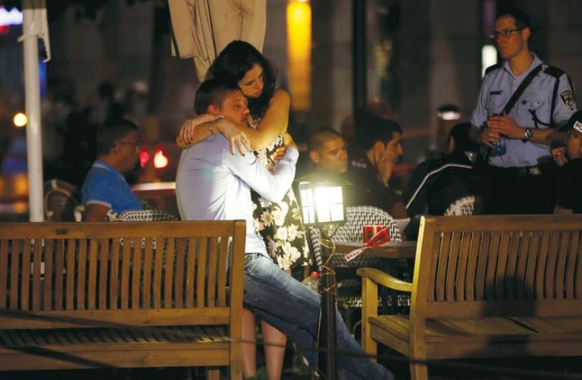 A man and woman comfort each other following the terrorist attack in Tel Aviv last week (photo credit: REUTERS)