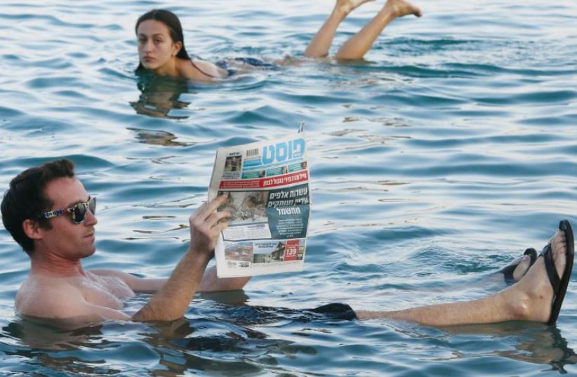 A man reads a newspaper while floating in the Dead Sea (photo credit: MARC ISRAEL SELLEM)