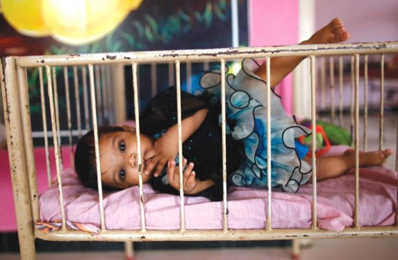 A BABY lies in her crib in this illustrative photo. ( (photo credit: REUTERS)