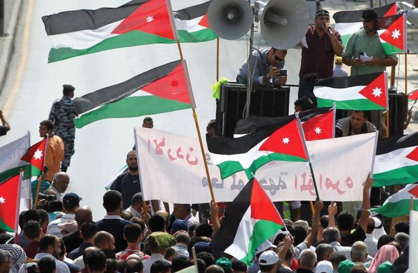 PROTESTERS IN Jordan hold Jordanian and Palestinian flags as they march in protest against Israel. (photo credit: REUTERS)