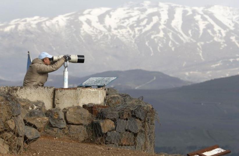 A member of the United Nations Disengagement Observer Force (UNDOF) looks through binoculars at Mount Bental, an observation post in the Israeli Golan Heights (photo credit: REUTERS)
