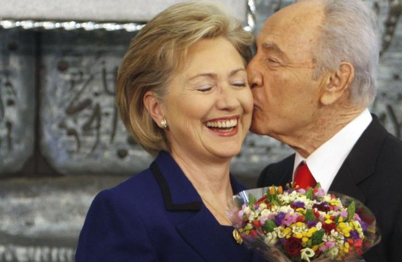 Shimon Peres kisses US Secretary of State Hillary Clinton as he gives her flowers after their meeting in Jerusalem, March 2009 (photo credit: REUTERS)