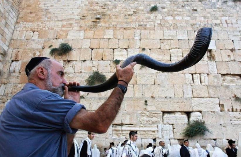 A worshiper blows a shofar at the Western Wall (photo credit: REUTERS)