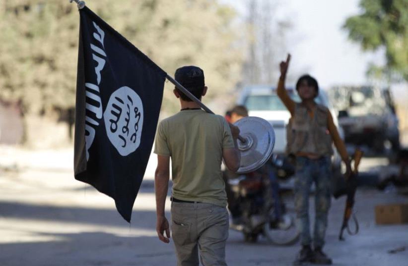 A rebel fighter takes away a flag that belonged to Islamic State militants in Akhtarin village, after rebel fighters advanced in the area, in northern Aleppo Governorate, Syria, October 7, 2016 (photo credit: REUTERS)