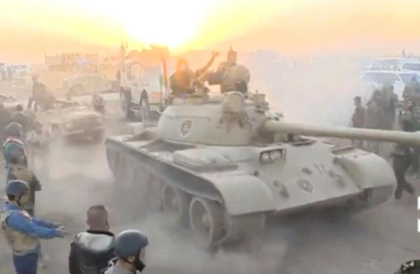 Tanks move past soldiers in military fatigues as the sun begins to set east of Mosul, where the Iraqi government launched a US-backed offensive to drive Islamic State from the northern city, in this still image taken from video released October 17, 2016 (photo credit: REUTERS)