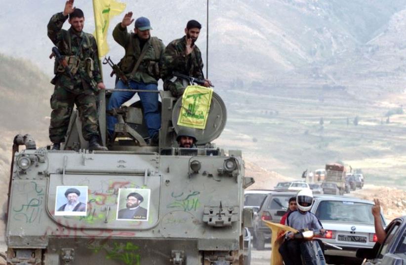 Pro-Iranian Hezbollah guerrillas, riding on an APC M113 used by pro-Israeli militiamen, wave to passing motorists as they drive in the former Israeli security zone in the Tell Nahas area of south Lebanon May 26, 2000.  (photo credit: REUTERS)