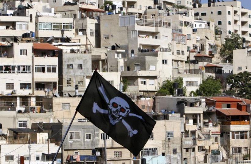 Protesters against Jewish settlement activity in the Silwan neighbourhood, outside the old city in Jerusalem hold a skull and bones flag (photo credit: REUTERS)