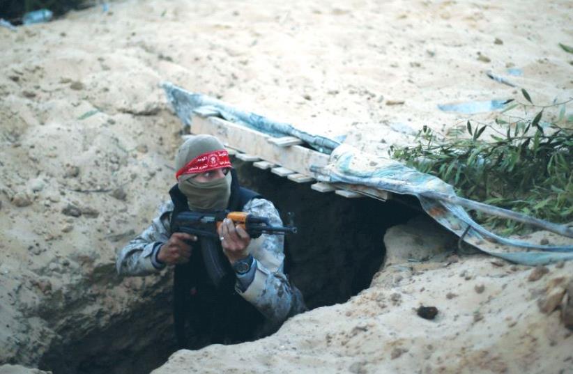 A PALESTINIAN TERRORIST climbs out of a tunnel in the Gaza Strip during a graduation ceremony in Rafah earlier this month. (photo credit: SUHAIB SALEM / REUTERS)