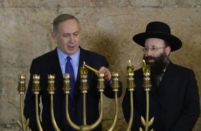 Prime Minister Benjamin Netanyahu Lighting Hanukkah candles at the Kotel (photo credit: AMOS BEN-GERSHOM/GPO)