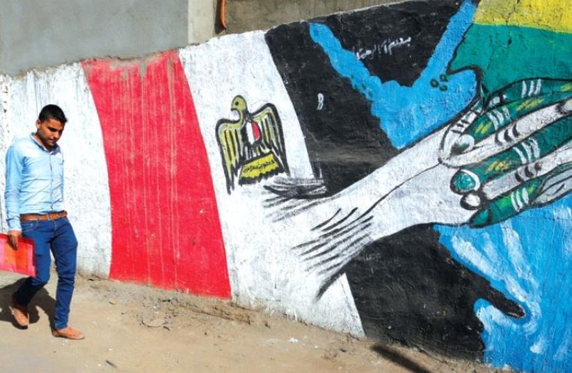 A man walks past graffiti depicting relations between Egypt and Saudi Arabia in Cairo, October 12 (photo credit: REUTERS)