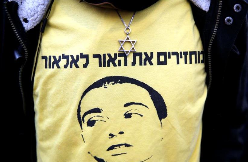 A supporter of Israeli soldier Elor Azaria, who is charged with manslaughter by the Israeli military, wears a shirt depicting Azaria with the words in Hebrew "Bringing the light back to Elor" during a protest outside the military court in Tel Aviv on the verdict day for the soldier, Tel Aviv, Israel (photo credit: REUTERS)